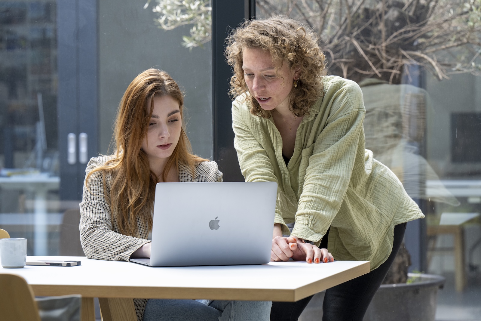 Twee personen achter bureau kijkend naar laptop.